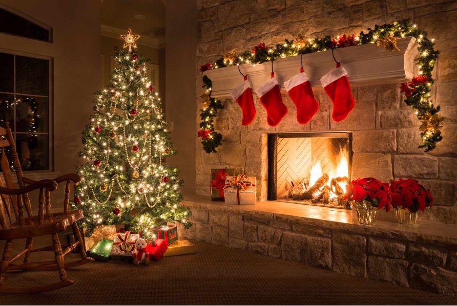 Presents under a Christmas tree in a room with cheery fire in fireplace
