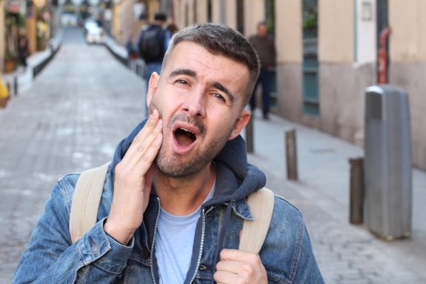 A person with his mouth open holding their jaw. Finding Lasting TMJ Relief