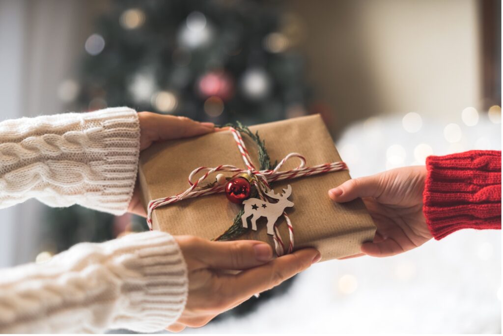 Hands holding a wrapped present, Unwrap the Joy: 12 Orthodontic Tips for a Twinkling Holiday Smile