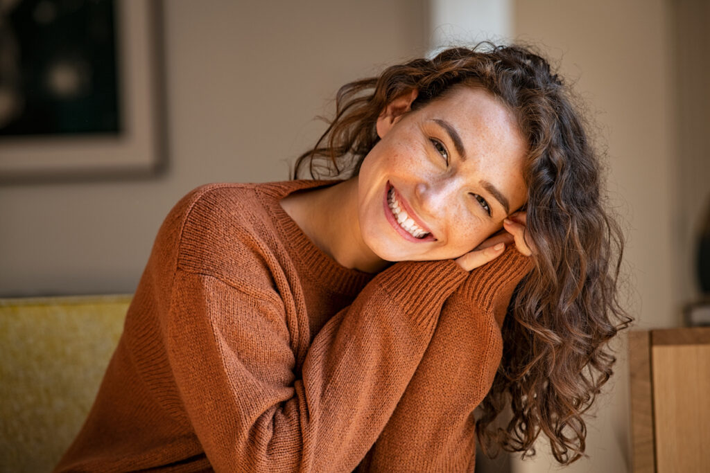 A person smiling with her hands on her head, Braces Myths Busted: What You Need to Know