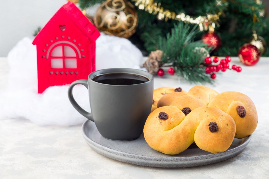 Traditional Swedish and scandinavian Christmas saffron buns Lussekatter with cup of coffee, Christmas decoration on a background, horizontal
