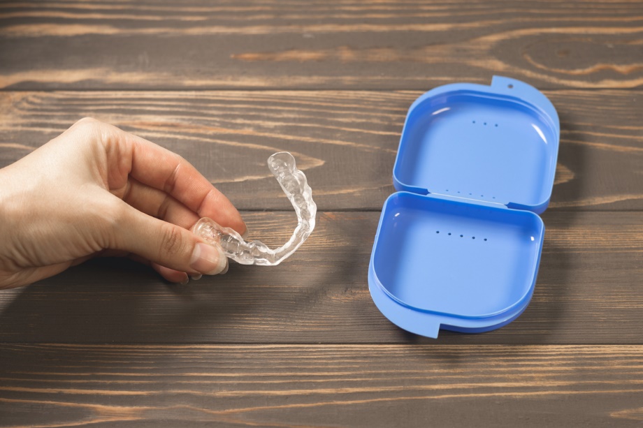 a person putting a set of clear aligners into a blue plastic protective case, Holiday Braces & Aligners Care: Protect Your Smile During Thanksgiving Feasts