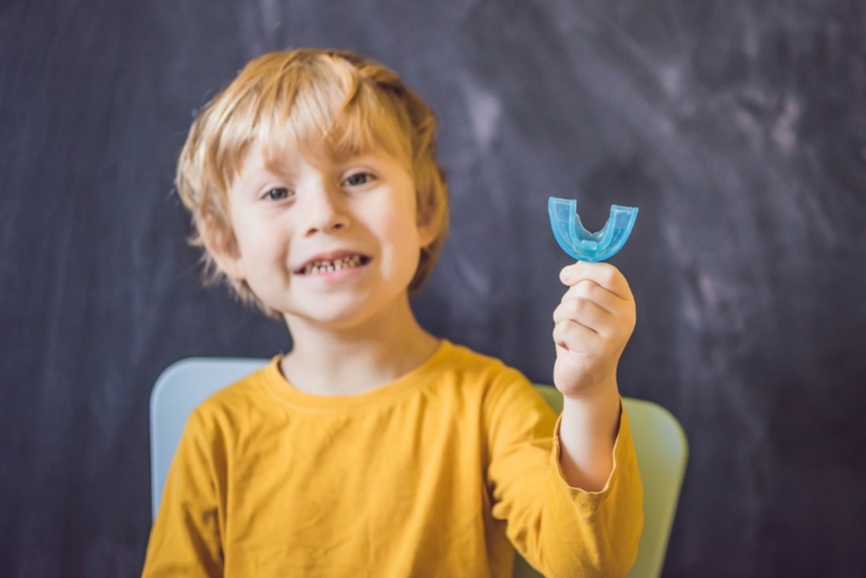 early orthodontic monitoring, A child holding a blue gumguard