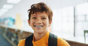 February Braces Guide for Kids and Teens: What to Skip (and What’s Still Safe!), A picture of a boy with braces smiling at the camera
