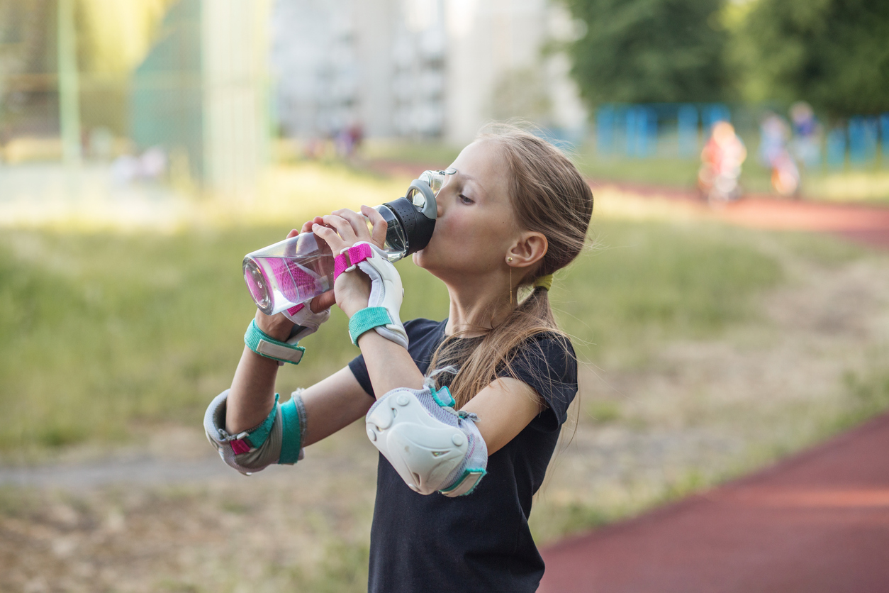 Teen staying hydrated with water during outdoor summer activities to support healthy orthodontic habits.