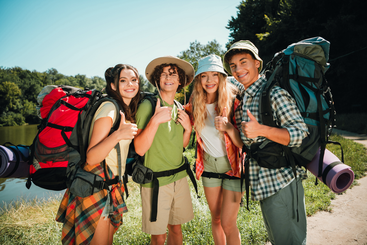 Teens preparing for a summer hiking adventure, highlighting the importance of staying on track with orthodontic treatment while traveling.