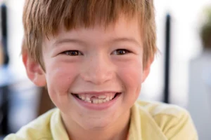 Smiling child with a gap where a permanent tooth has not yet come in.